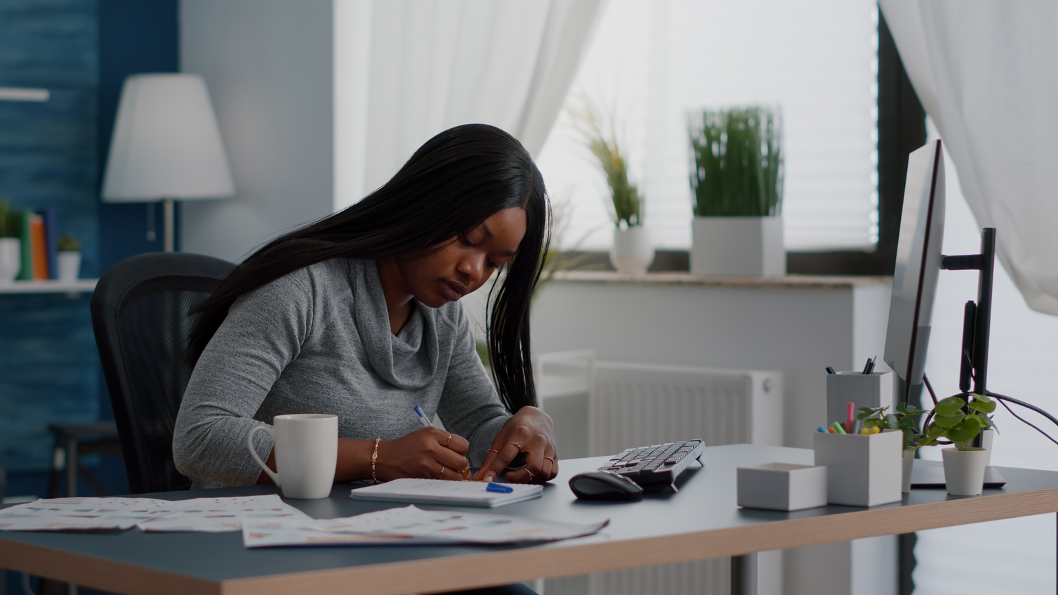 Black student writing education ideas on stickey notes sitting at desk table in living room tailored ehs training courses