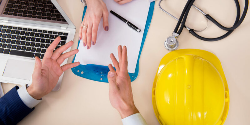 Doctor and manager agreeing industrial insurance coverage employee safety handbook
